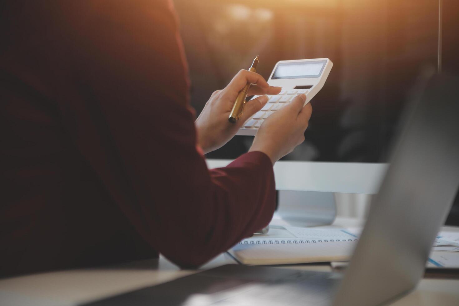 Cropped image of professional businesswoman working at her office via laptop, young female manager using portable computer device while sitting at modern loft, flare light, work process concept photo