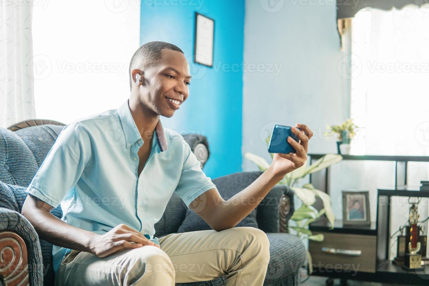 African young man using a smartphone on the day at home. photo