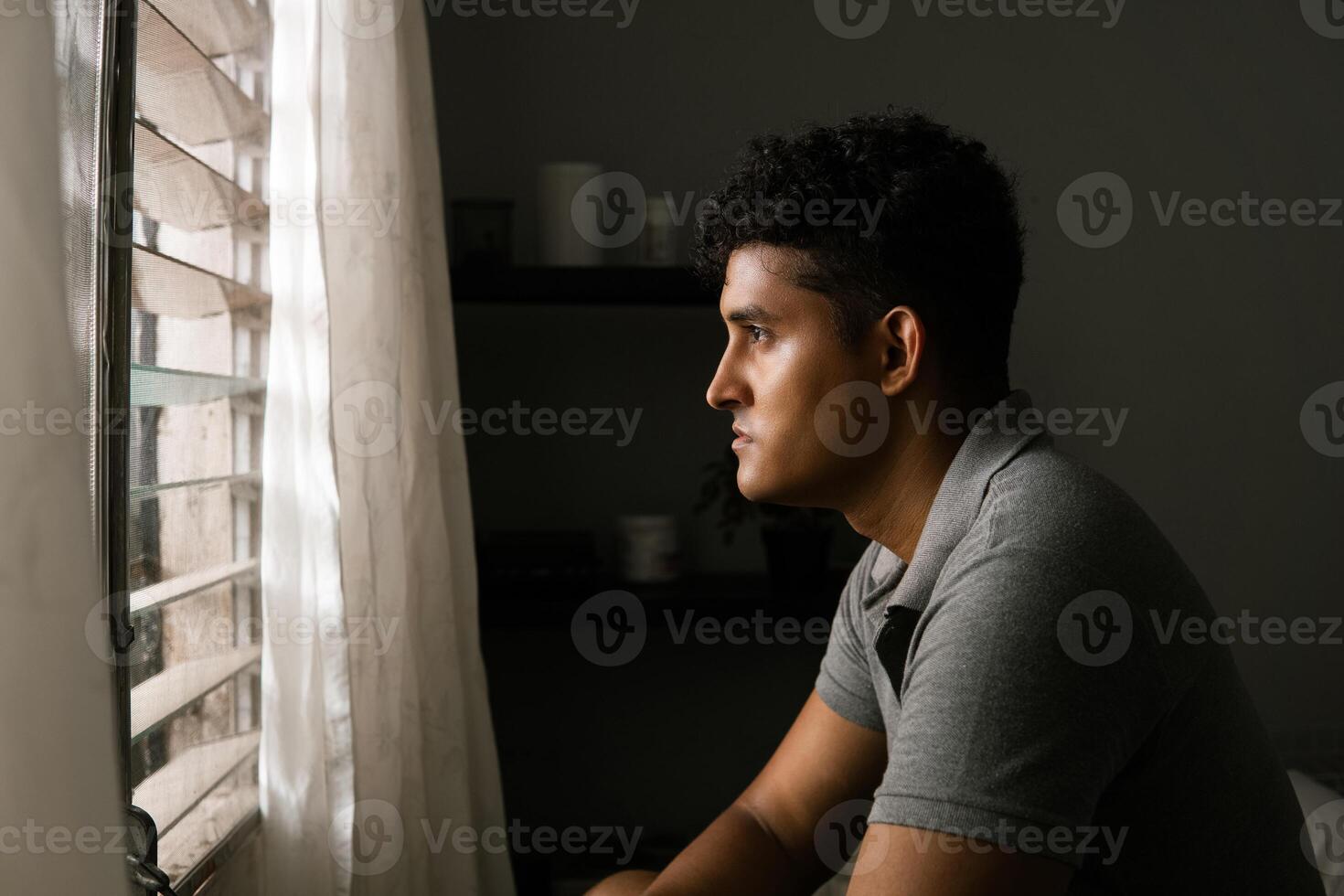 Lonely front facing man looking and thinking in front of a window. concept mental health and masculine crisis. photo