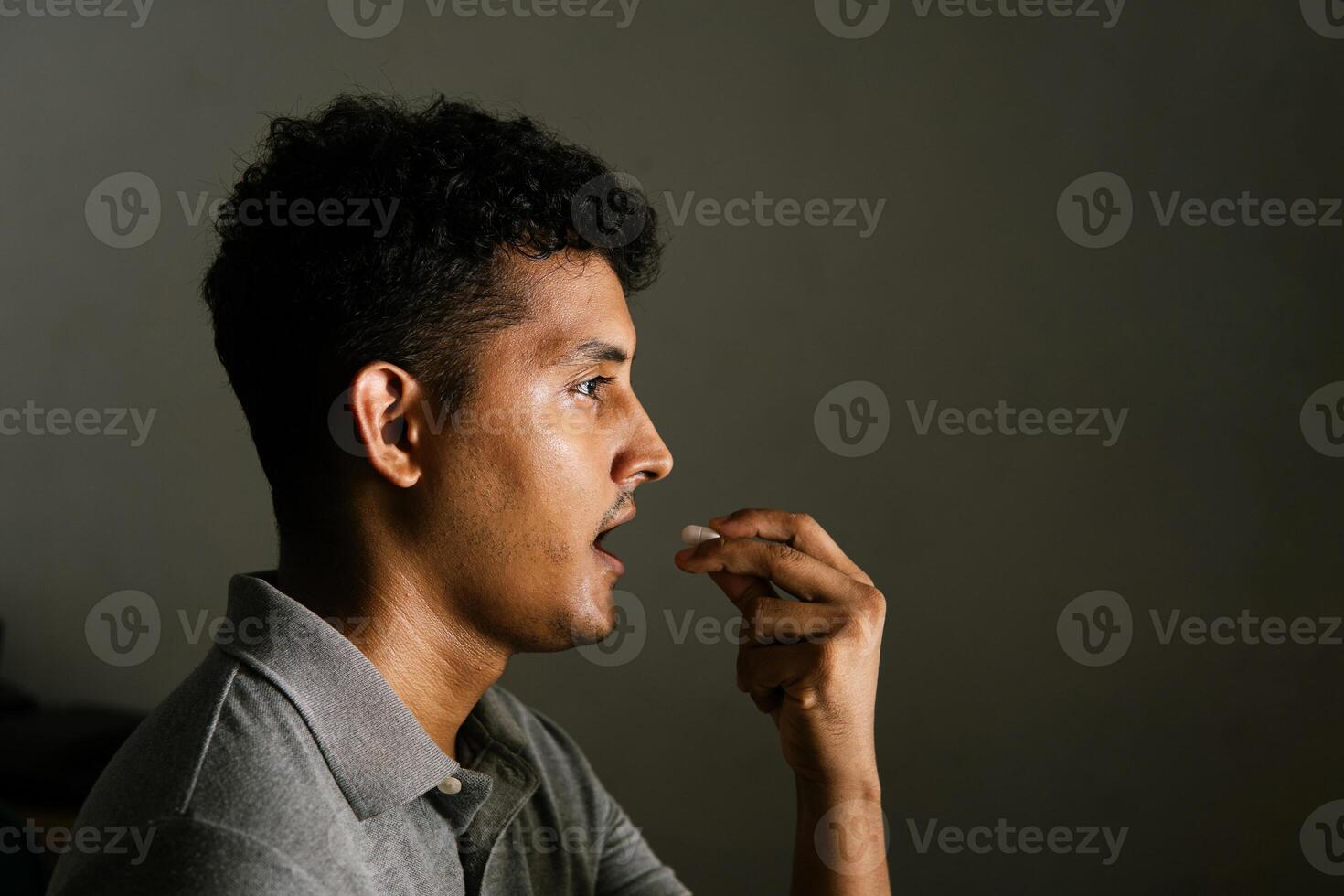 Portrait of side view of man taking a drug capsule. Depression concept. photo