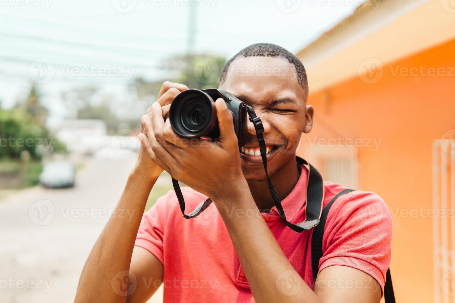 Young stylish male photographer using camera while exploring the city photo