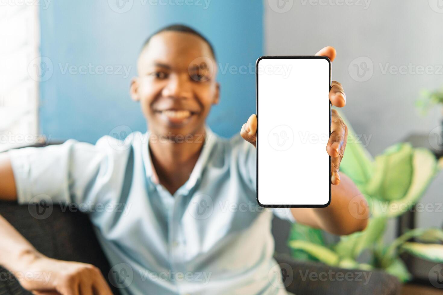 smiling man showing mobile phone blank white screen mockup to camera. photo