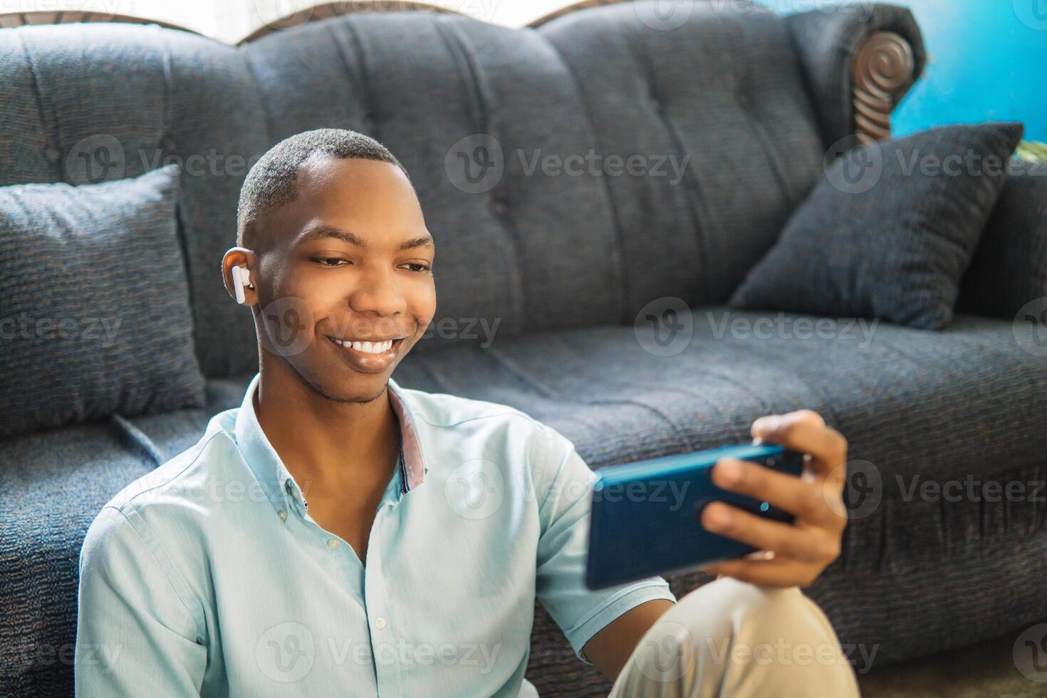 Happy boy watching and listening to on phone sitting on a sofa at home. photo