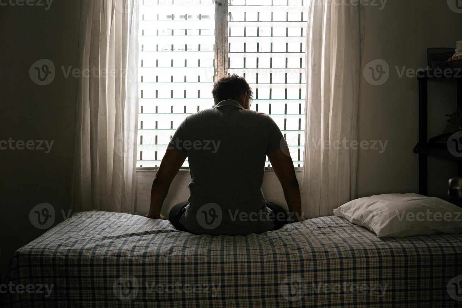 Desperate man in silhouette sitting on the bed alone. masculinity and emasculation concept. photo