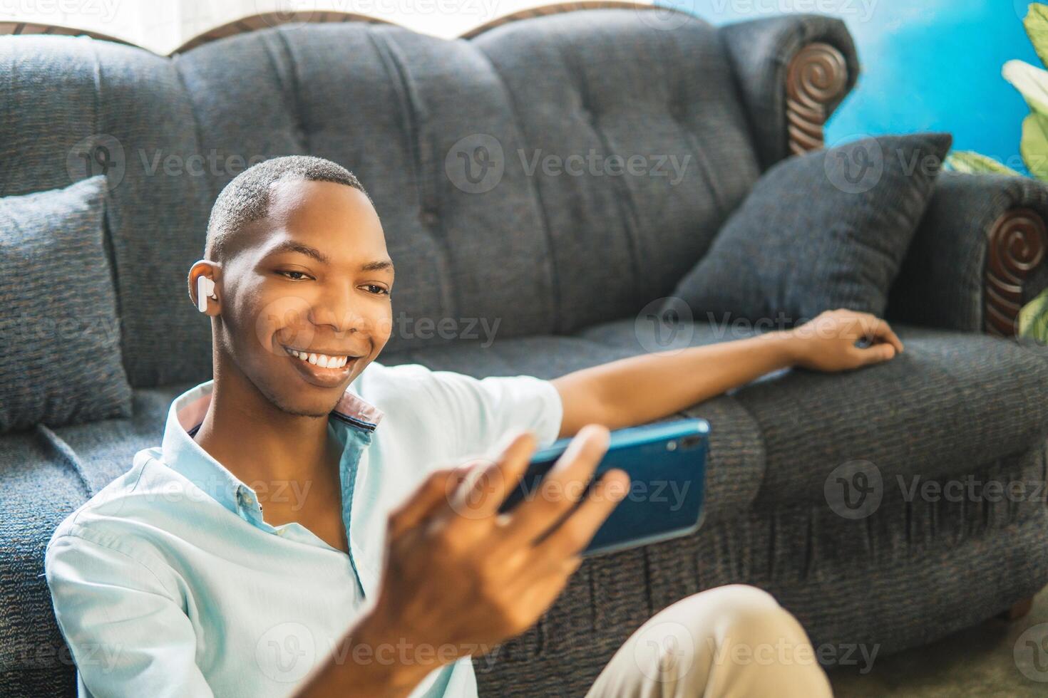Happy boy watching and listening to on phone sitting on a sofa at home. photo