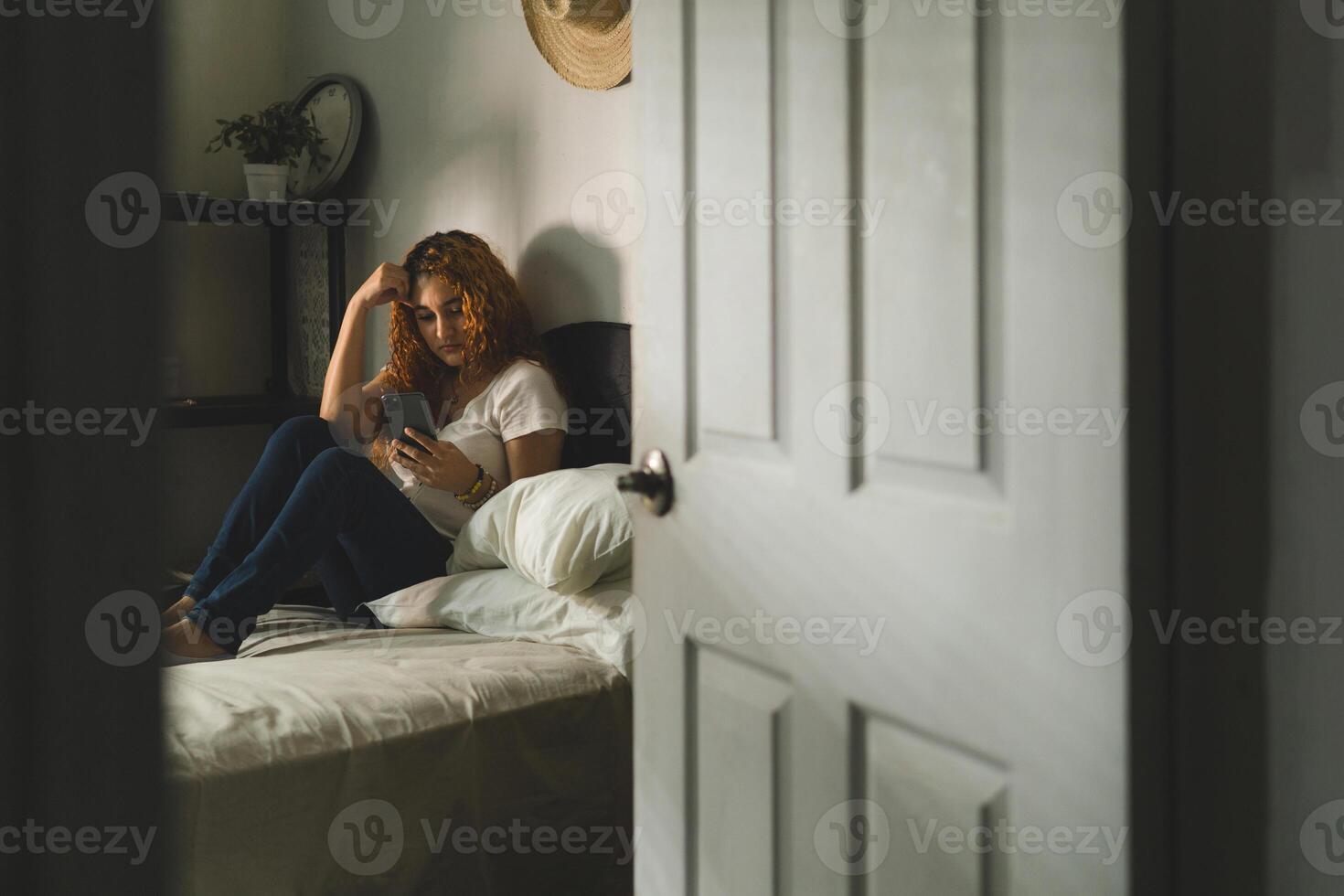 Sad teen waiting for phone message on the floor at home photo