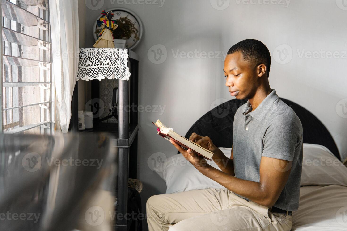 Portrait side view of man holding and reading a bible in his room. Religious concept. photo