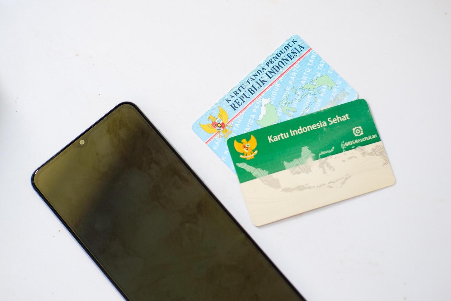 smartphone and cards of identity and healthcare insurance of Indonesian people on the white table photo