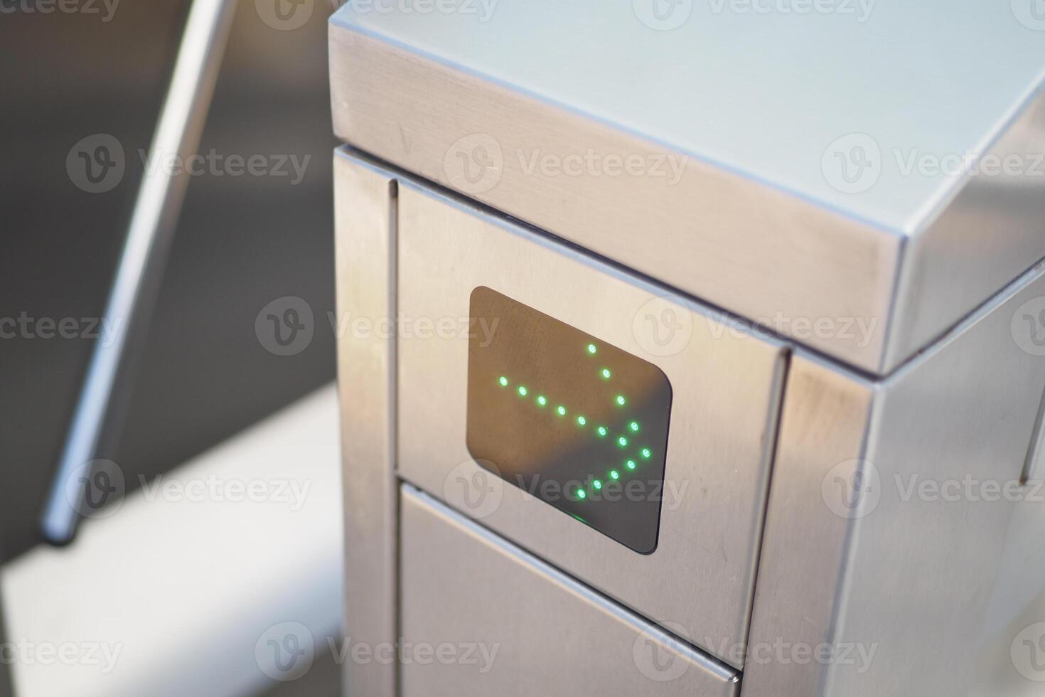 Modern turnstile gate with green arrow indicator for direction control at access checkpoint photo