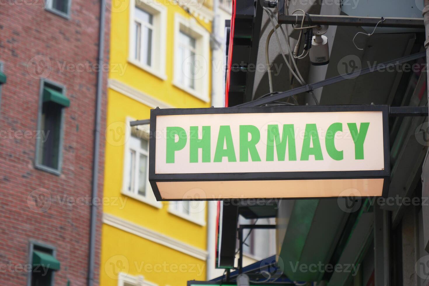 A colorful building background with a visible pharmacy sign in the urban street view photo
