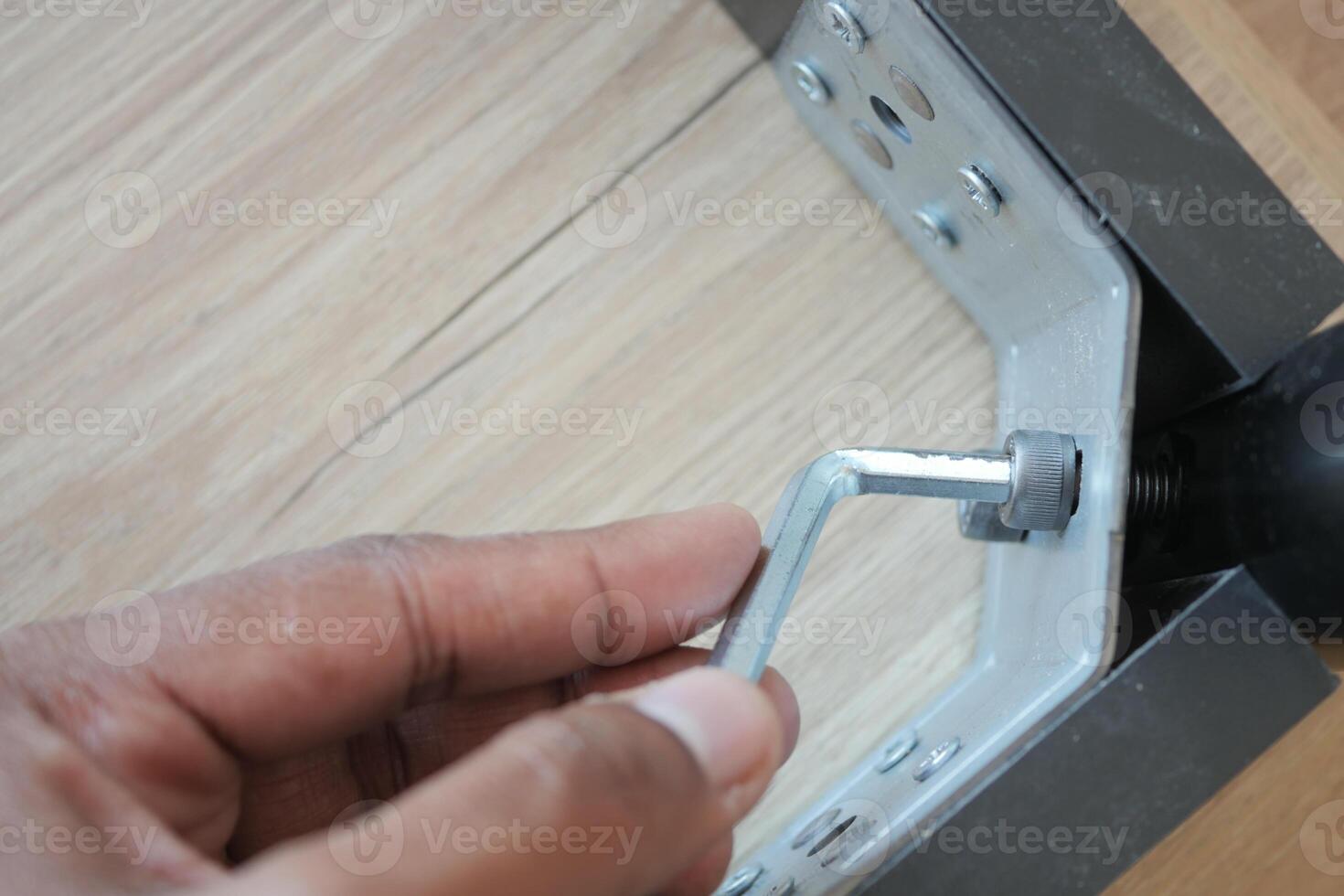 Using a wrench, theyre removing a screw from metal photo