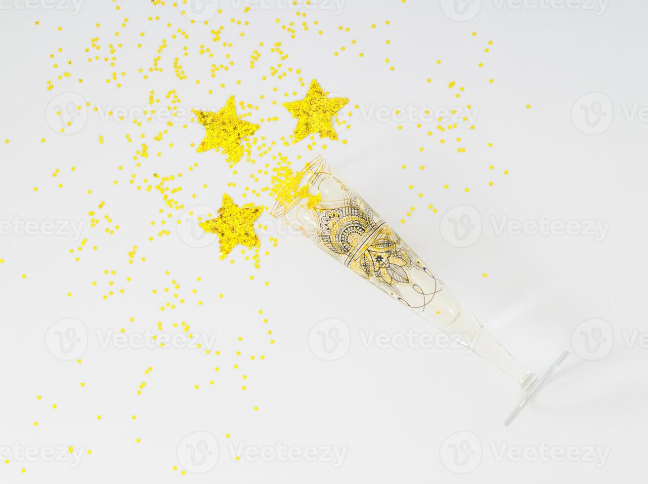 Creative layout made with champagne glass and golden glitter stars confetti on white background. Festive holiday backdrop. Minimal party concept. Luxury flat lay composition. photo