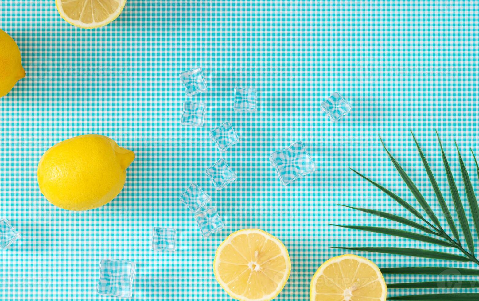 Summer creative layout made with lemons, ice cubes and tropical green palm leaf on white and blue background. Minimal summer fruit concept. Lemons aesthetic. Flat lay, top of view. photo