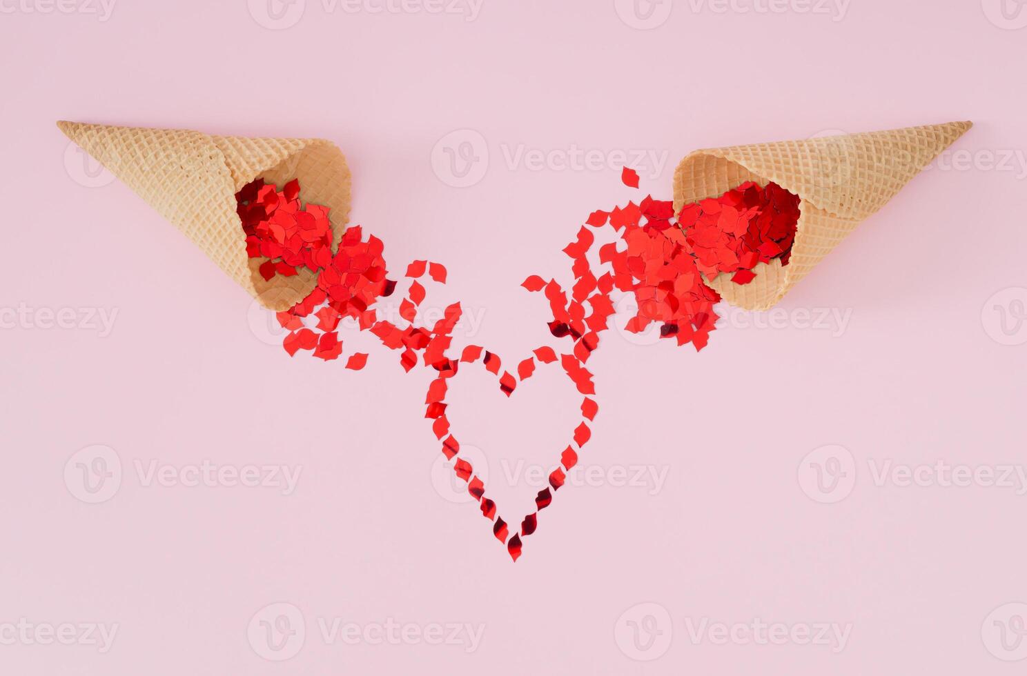 Red lips glitter confetti falling from ice cream cones and forming heart symbol on light pink background. Minimal summer love concept. Ice cream with love layout. Romantic style aesthetic idea. photo