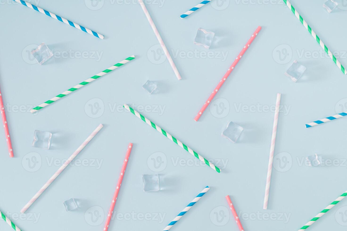 Trendy pattern made with ice cubes and various colorful paper drinking straws on pastel blue background. Summer drink minimal concept. Summertime pastel backdrop. Flat lay composition. photo
