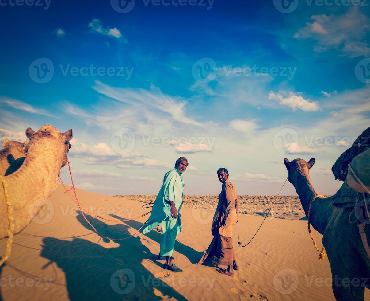 Two cameleers camel drivers with camels in dunes of Thar deser photo