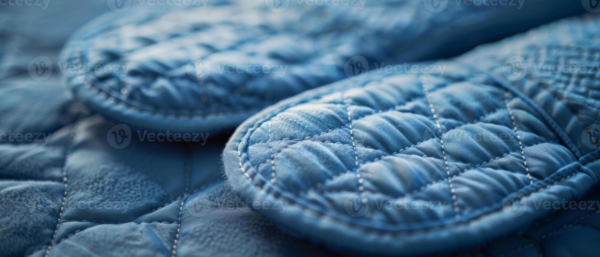 A detailed close-up of quilted blue slippers resting on a bed, showcasing soft and cozy texture. photo
