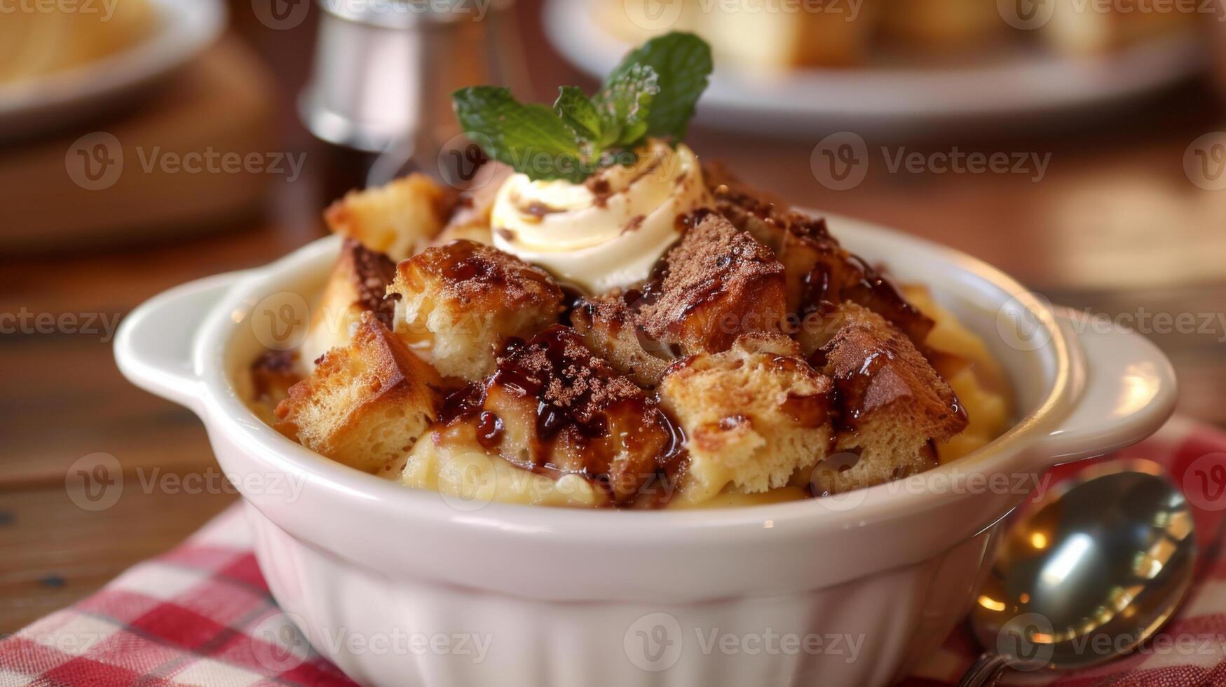 A bowl of delicious bread pudding dessert topped with whipped cream, mint, and drizzled with chocolate syrup. photo