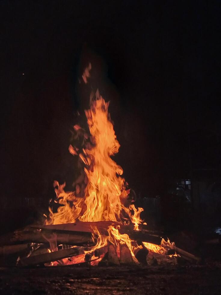 A large bonfire crackles and burns brightly in the darkness of night. photo