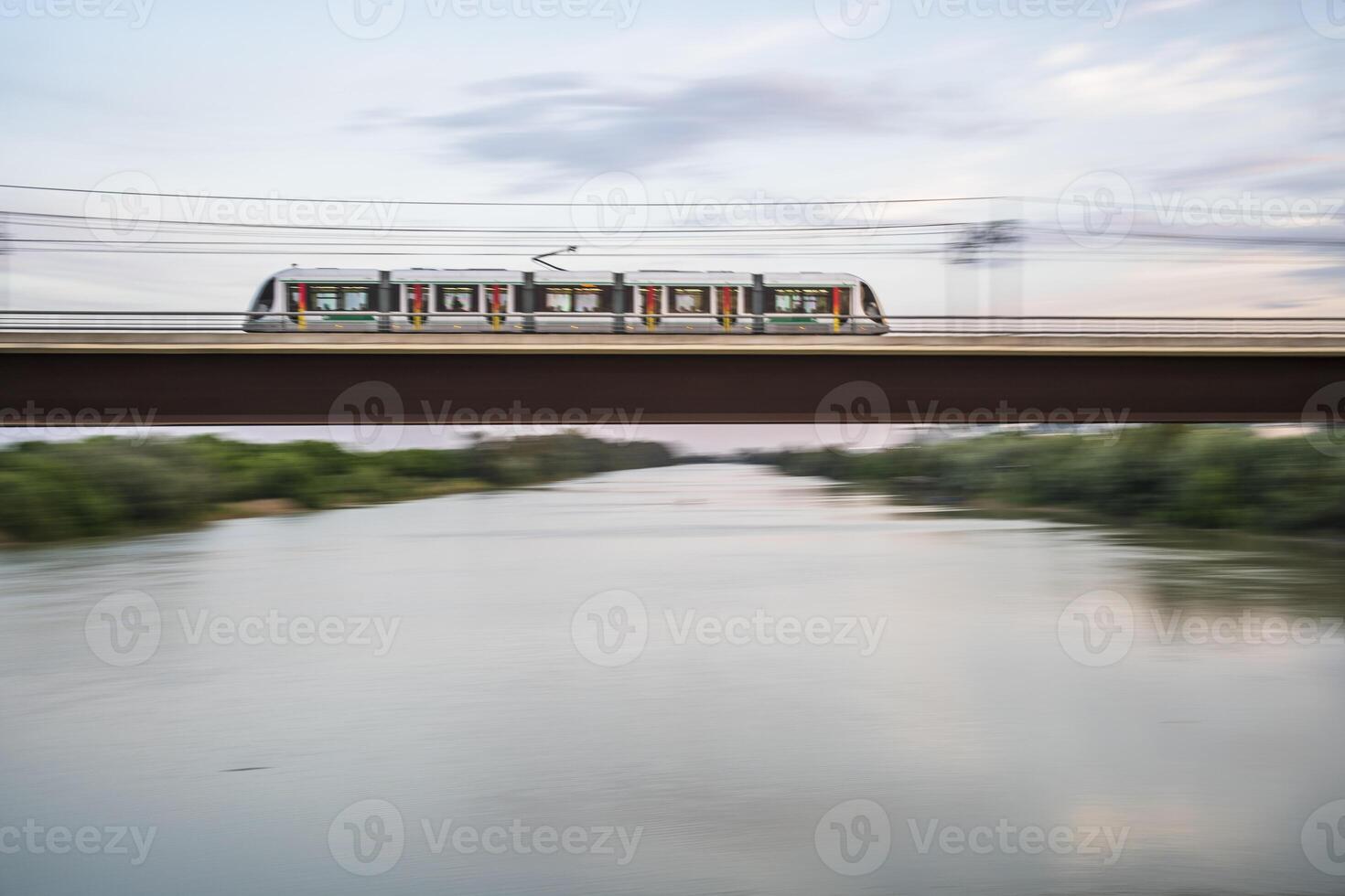 Panning shot of a train over the Guadalquivir river, San Juan de Aznalfarache, Seville, Spain photo