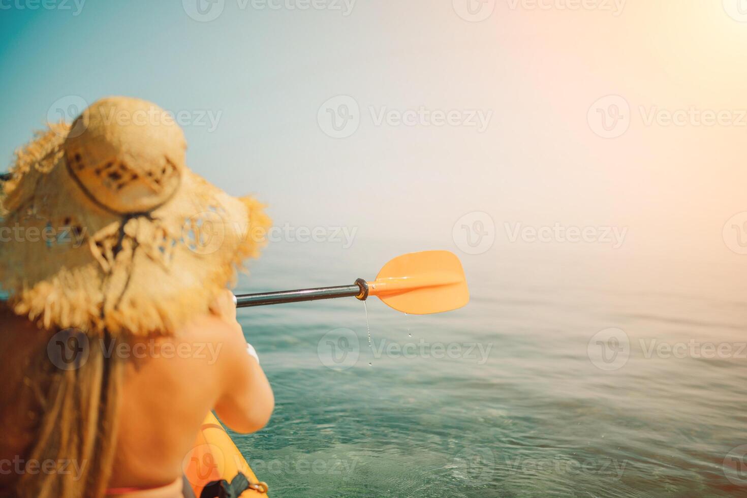 Woman in kayak back view. Happy woman with long hair in a swimsuit and hat floating in kayak on the sea. Summer holiday vacation. Summer holidays vacation at sea. photo