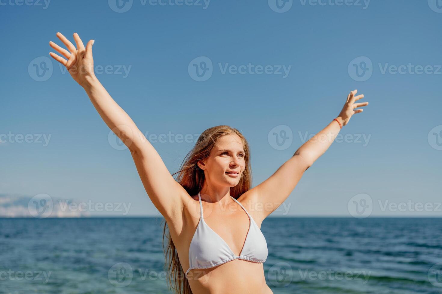 A woman with long hair is standing on the beach, wearing a bikini photo