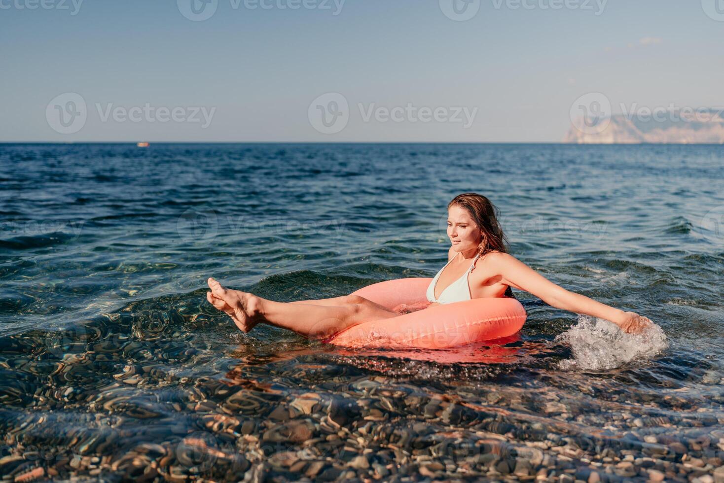 A woman is floating on a red inflatable tube in the ocean photo