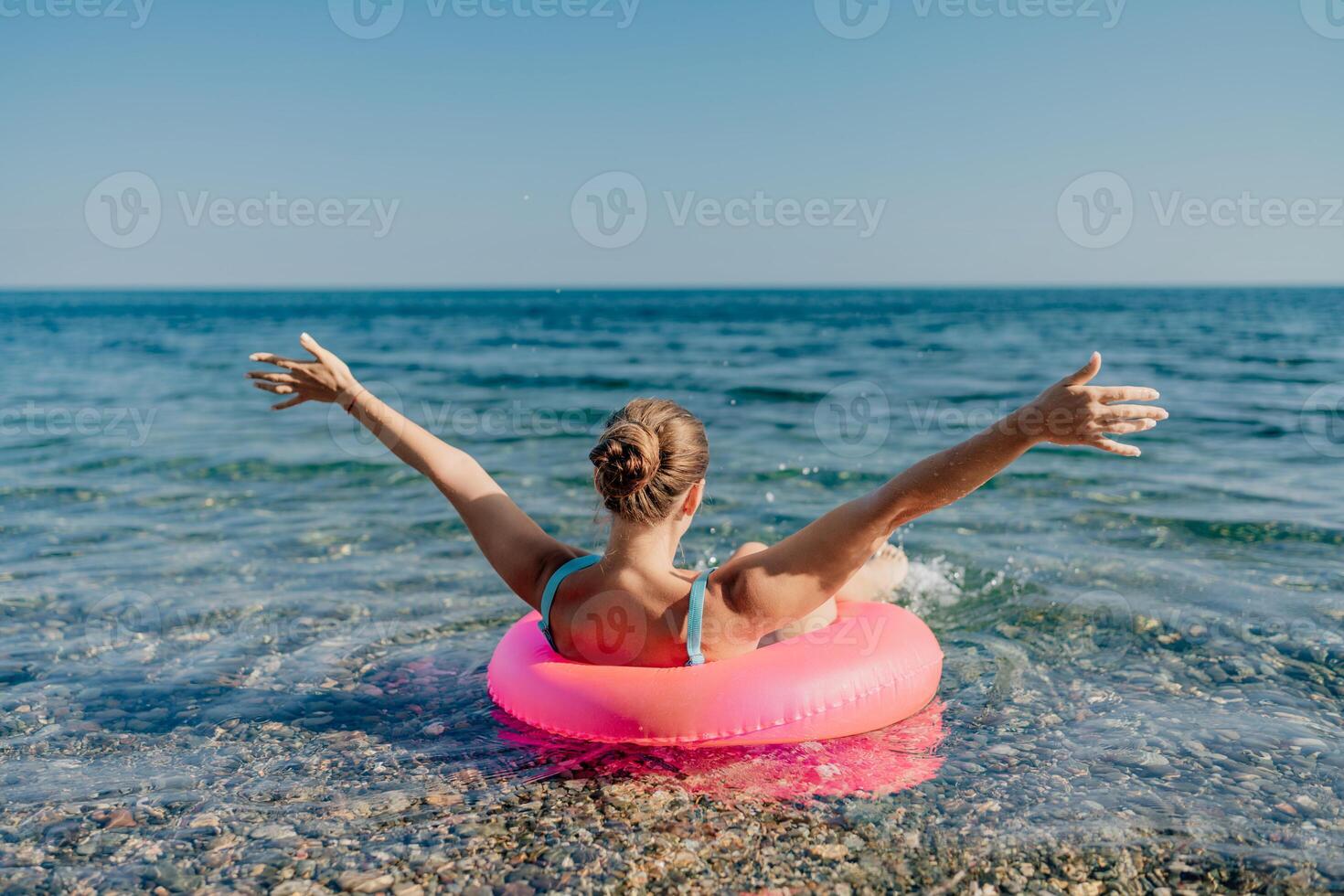 A woman is floating on a pink inflatable raft in the ocean photo