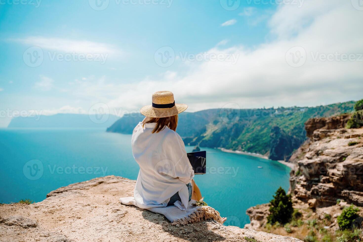 Freelance woman working on a laptop by the sea, typing away on the keyboard while enjoying the beautiful view, highlighting the idea of remote work. photo