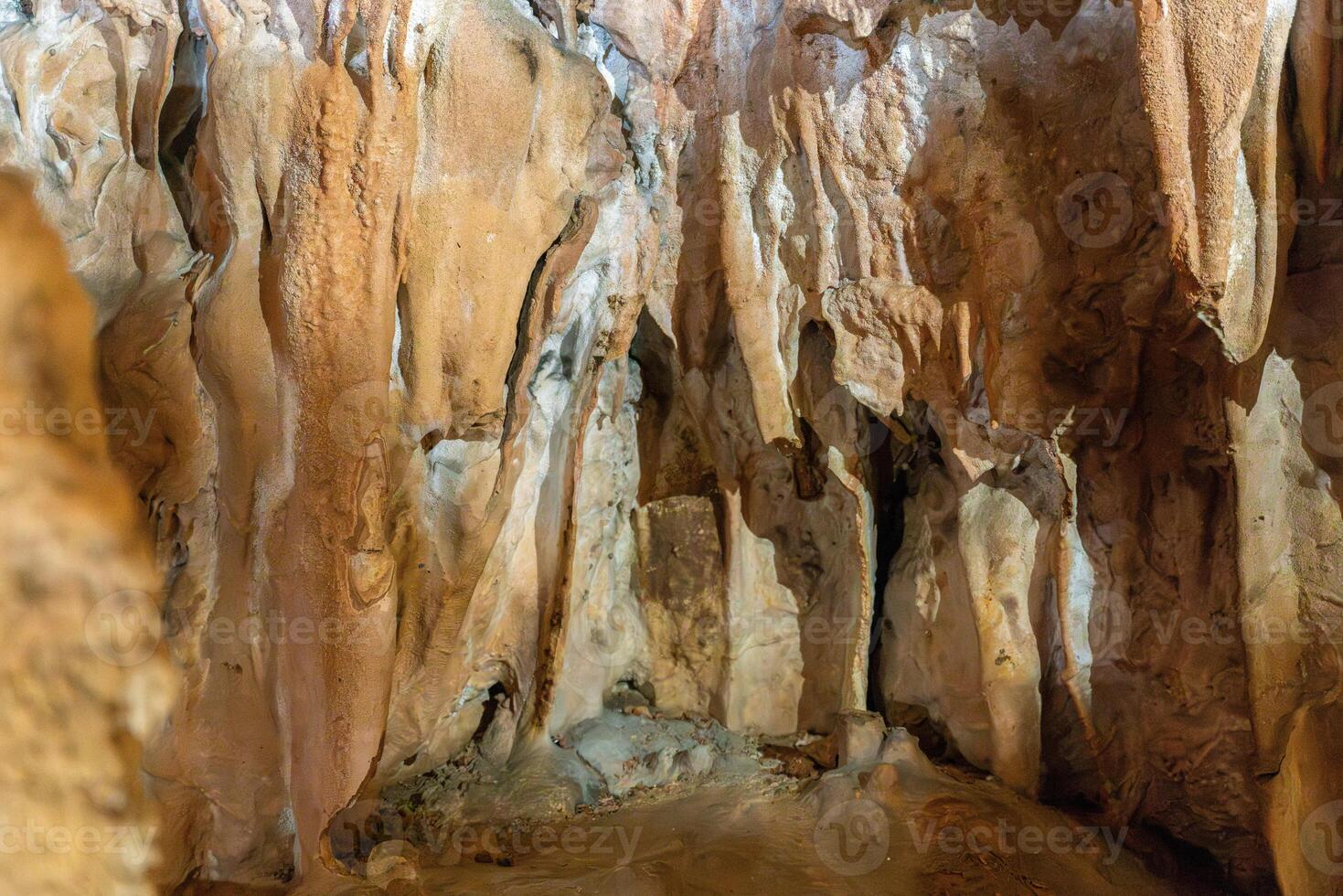 A cave with a lot of rocks and a lot of dirt. The cave is dark and the walls are brown. photo