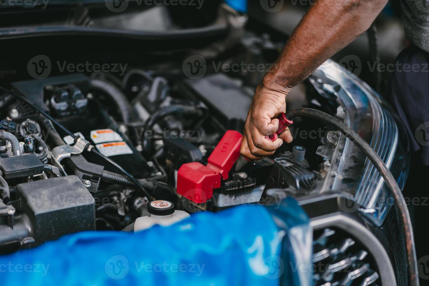 Closeup mechanic worker hand clamping car battery terminal for jump start low voltage battery vehicle in garage. photo