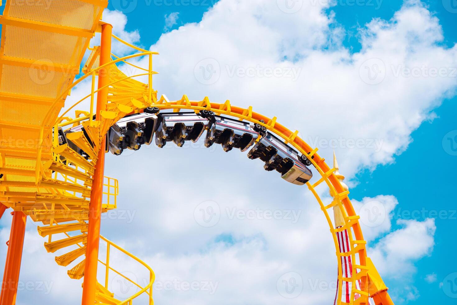 Yellow Roller coaster Roll loop curve high to blue sky summer season activity funny at amusement park. photo