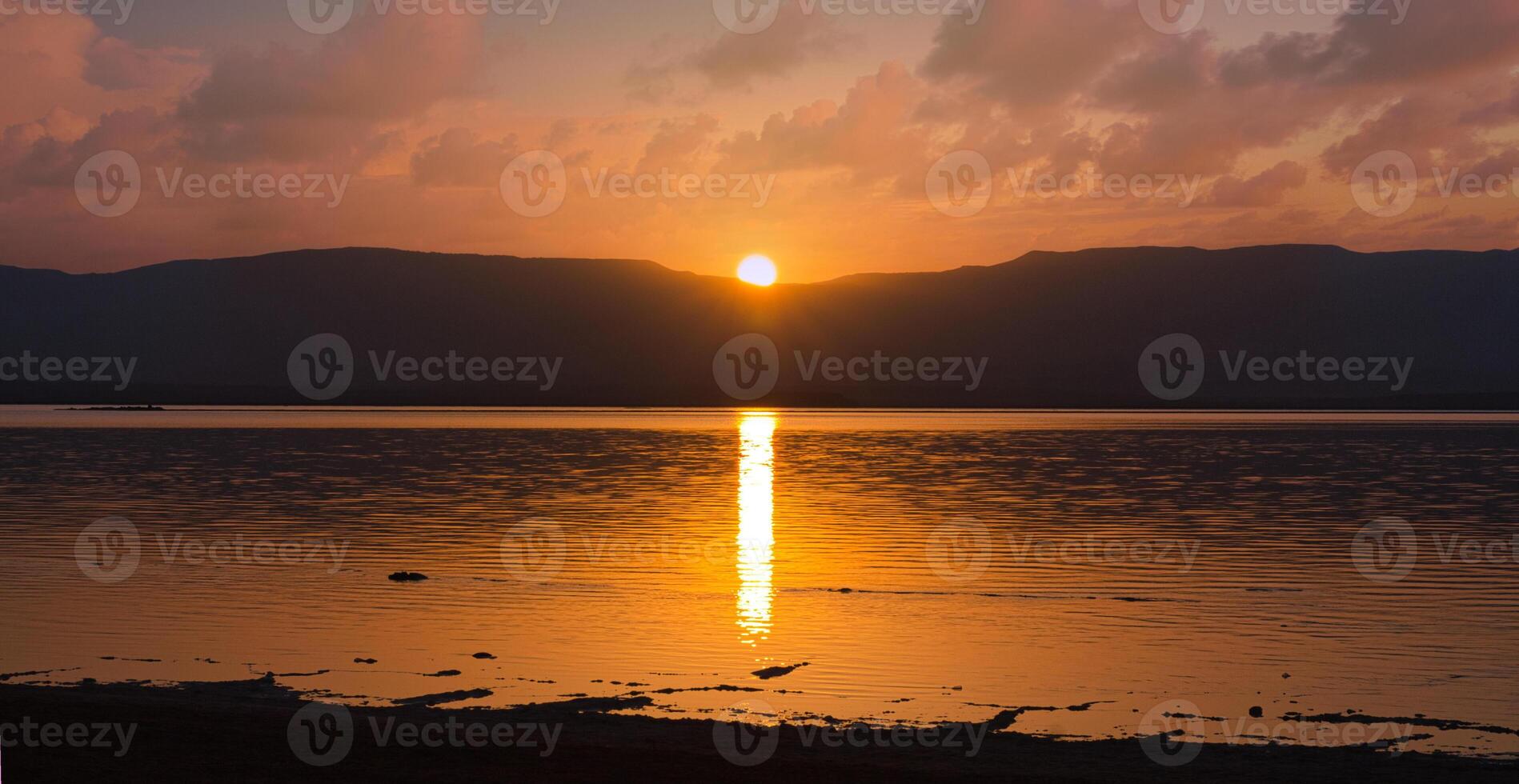 Shore of the Dead Sea, sunrise over the Jordanian mountains. Glowing path on the water. photo