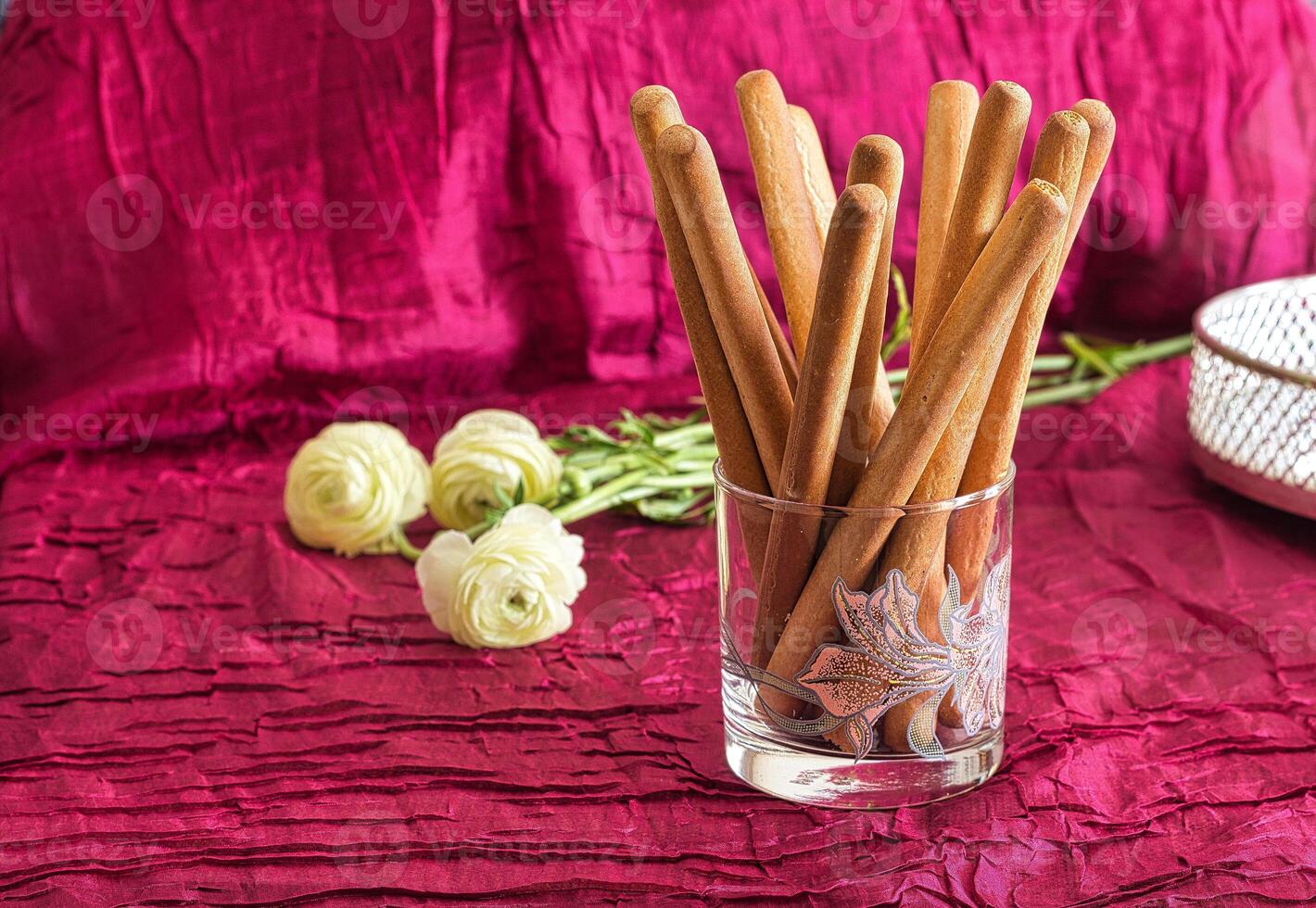 Grissini on the background of flowers and a red tablecloth. Breadsticks. Italian food. photo