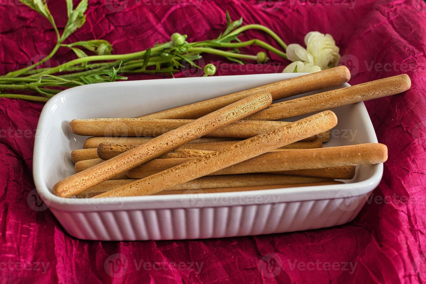 Grissini on the background of flowers and a red tablecloth. Breadsticks. Italian food. photo
