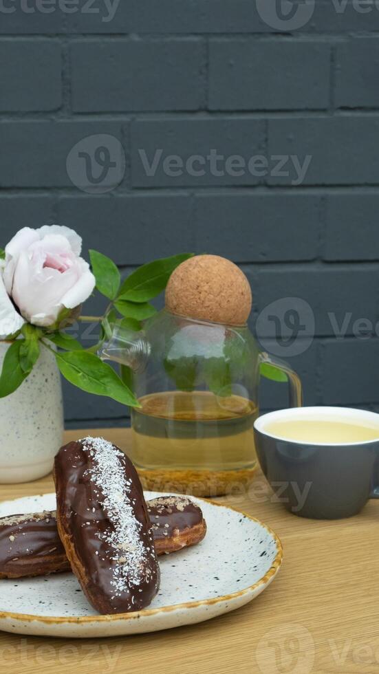Eclairs with tea on wooden table in a cafe. Sweet food still life photo