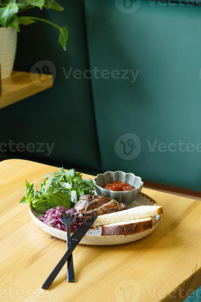 Plate of fried pork meat with sauce and greens photo