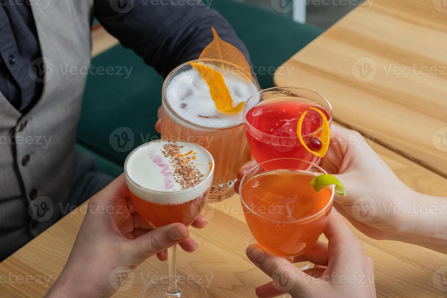 Cheers with alcoholic cocktails in hands. Elegant party with friends in a bar. photo