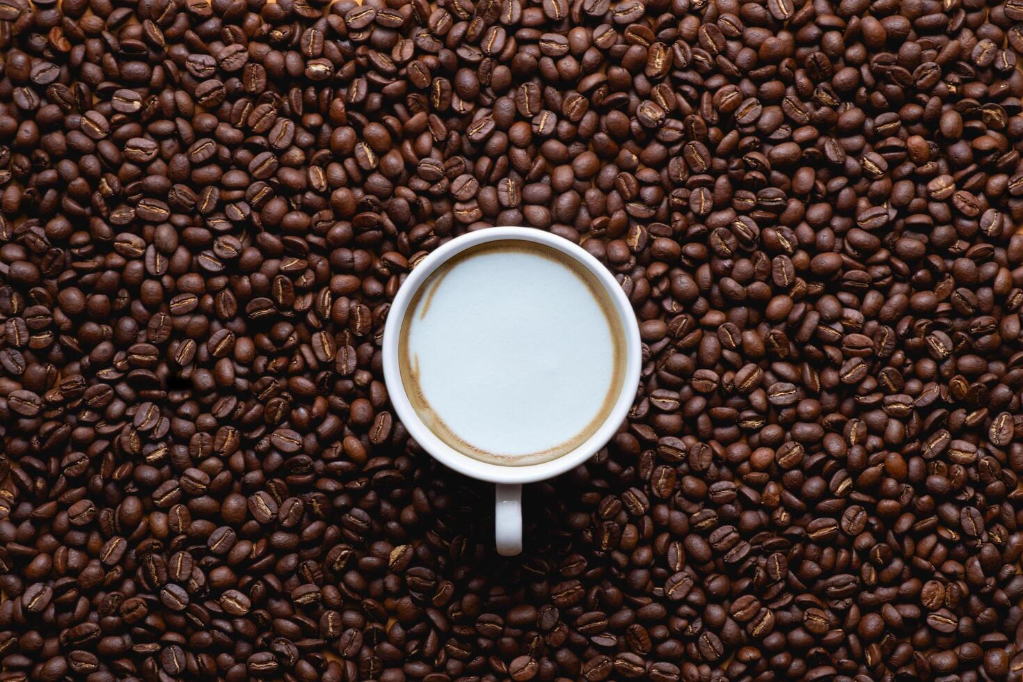 Close up of roasted coffee beans with foam top view on dark wooden background photo