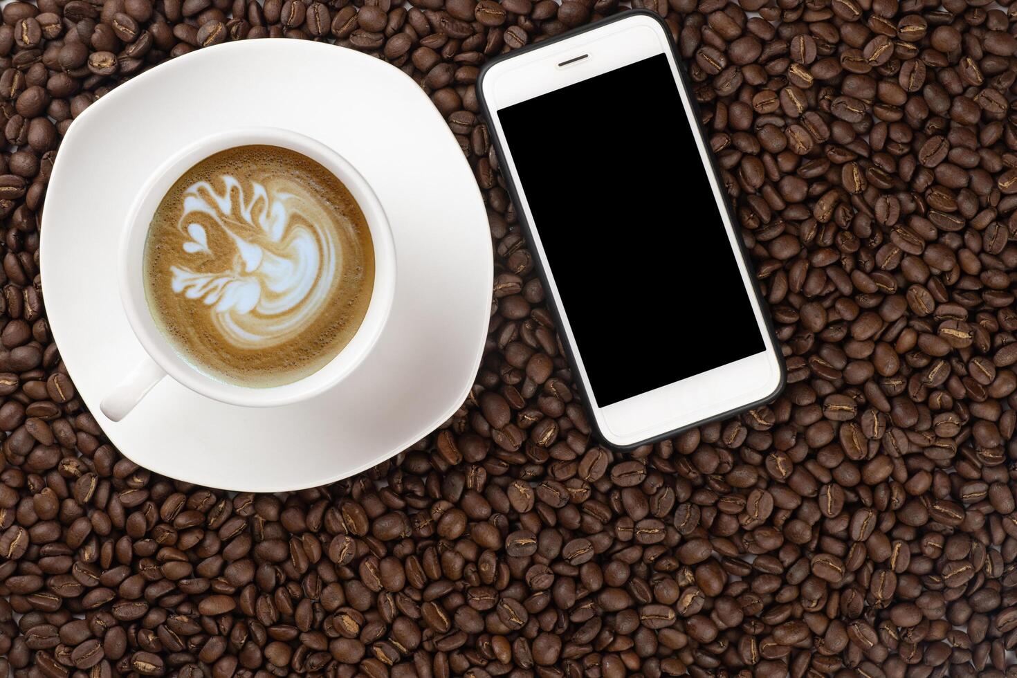 Close up of roasted coffee beans with foam top view on dark wooden background photo