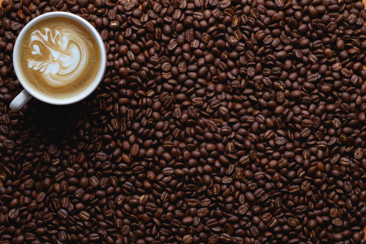 Close up of roasted coffee beans with foam top view on dark wooden background photo