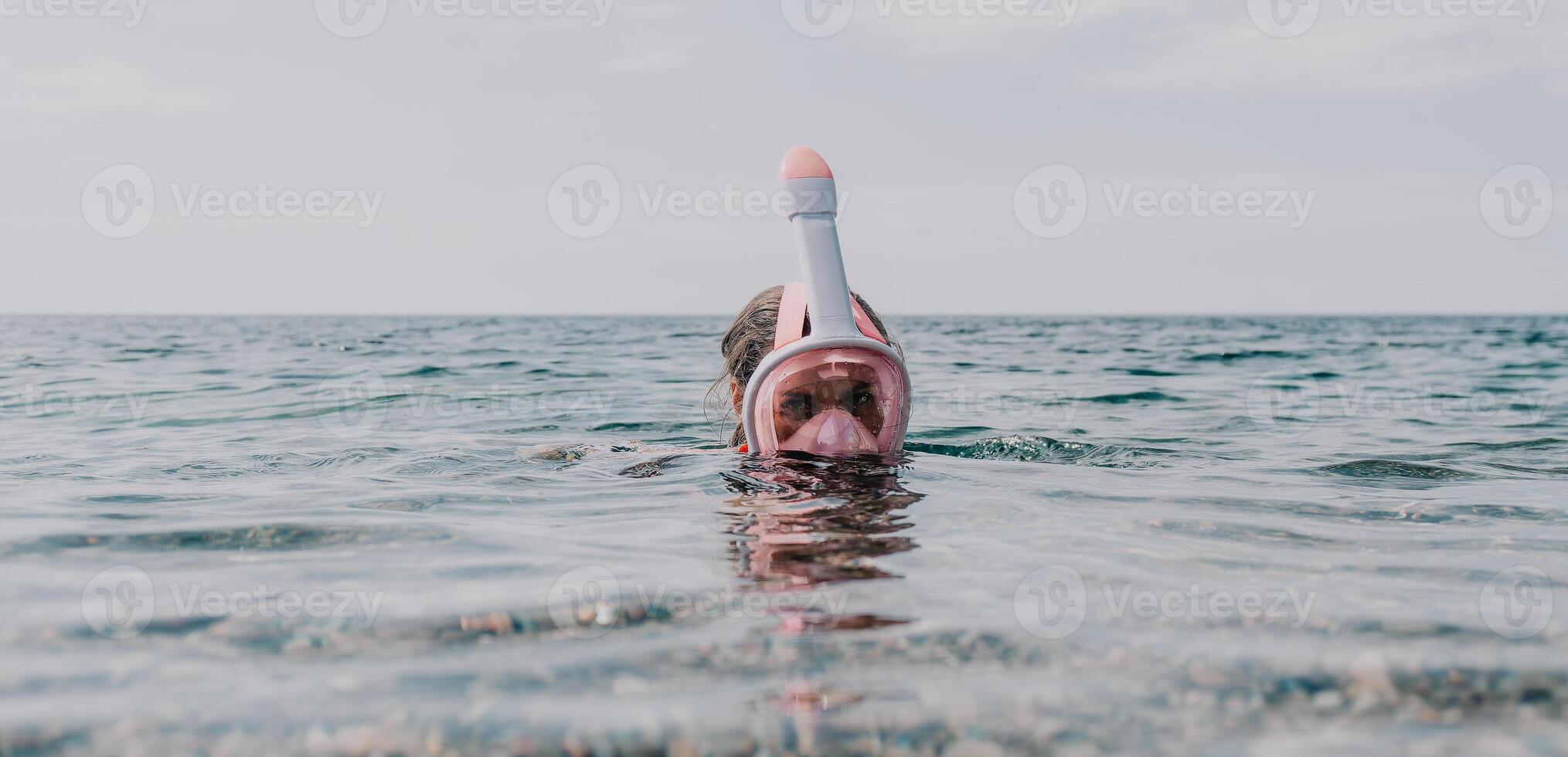 Young happy woman in white bikini and wearing pink mask gets ready for sea snorkeling. Positive smiling woman relaxing and enjoying water activities with family summer travel holidays vacation on sea. photo
