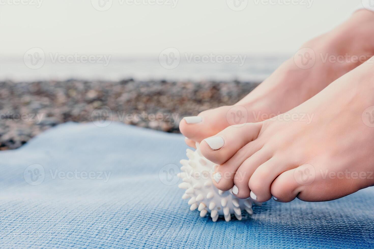 Woman sea yoga. Well looking middle aged woman with braids dreadlocks in white leggings and tops doing stretching pilates on yoga mat near sea. Female fitness yoga routine concept. Healthy lifestyle. photo