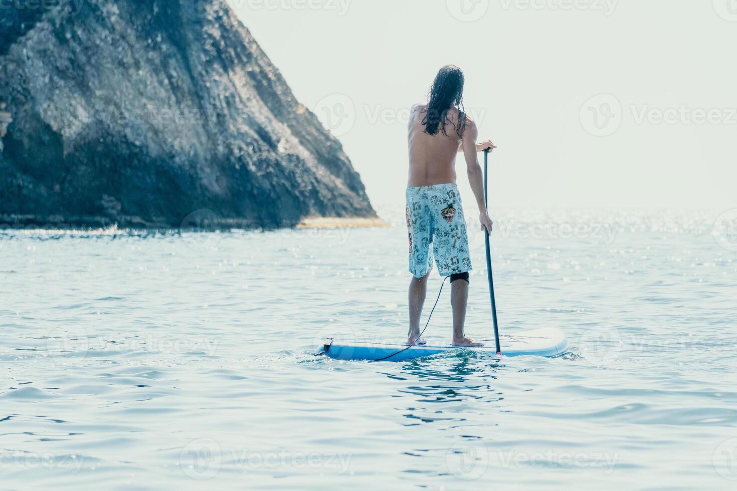 Man Sup Sea. Strong athletic man learns to paddle sup standing on board in open sea ocean on sunny day. Summer holiday vacation and travel concept. Aerial view. Slow motion photo