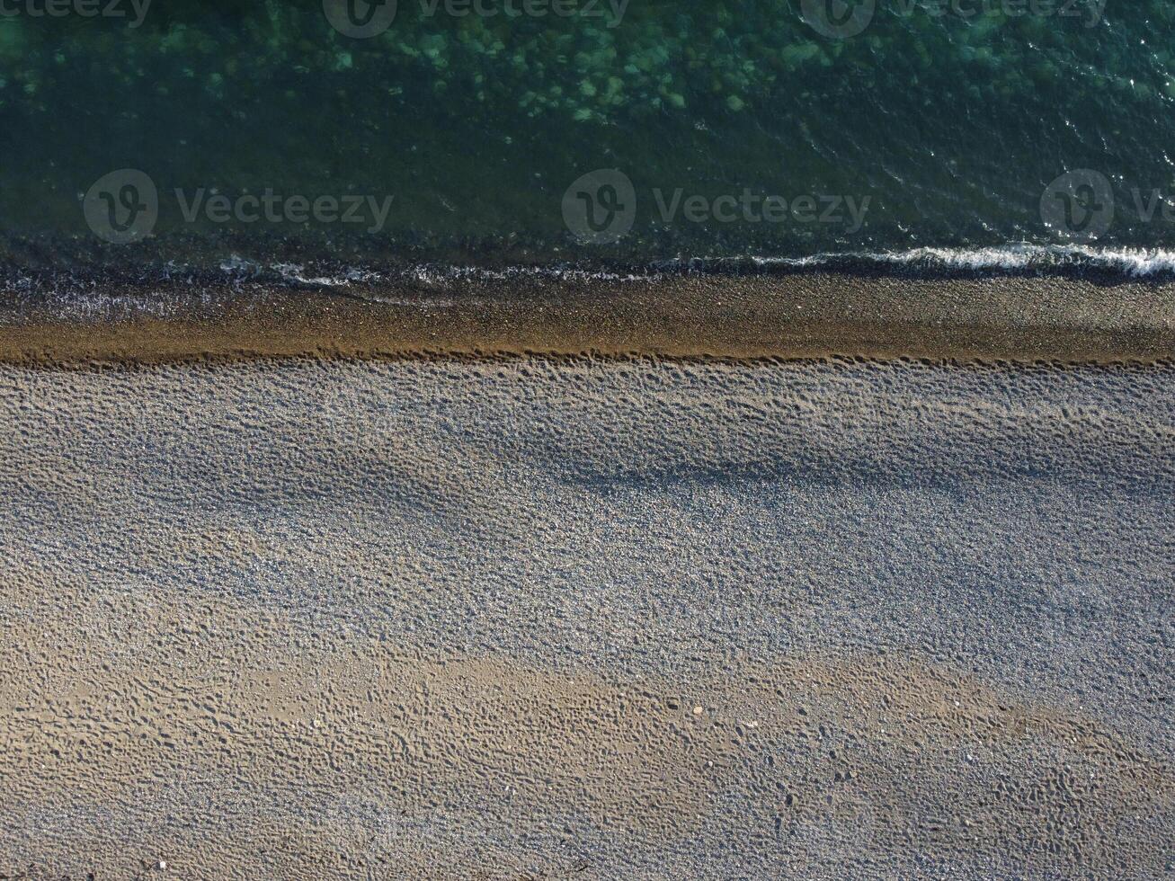 Aerial view from above on azure sea and pebbles beach. Small waves on cristal clear water surface in motion blur. Nature summer ocean sea beach background. Nobody. Holiday, vacation and travel concept photo