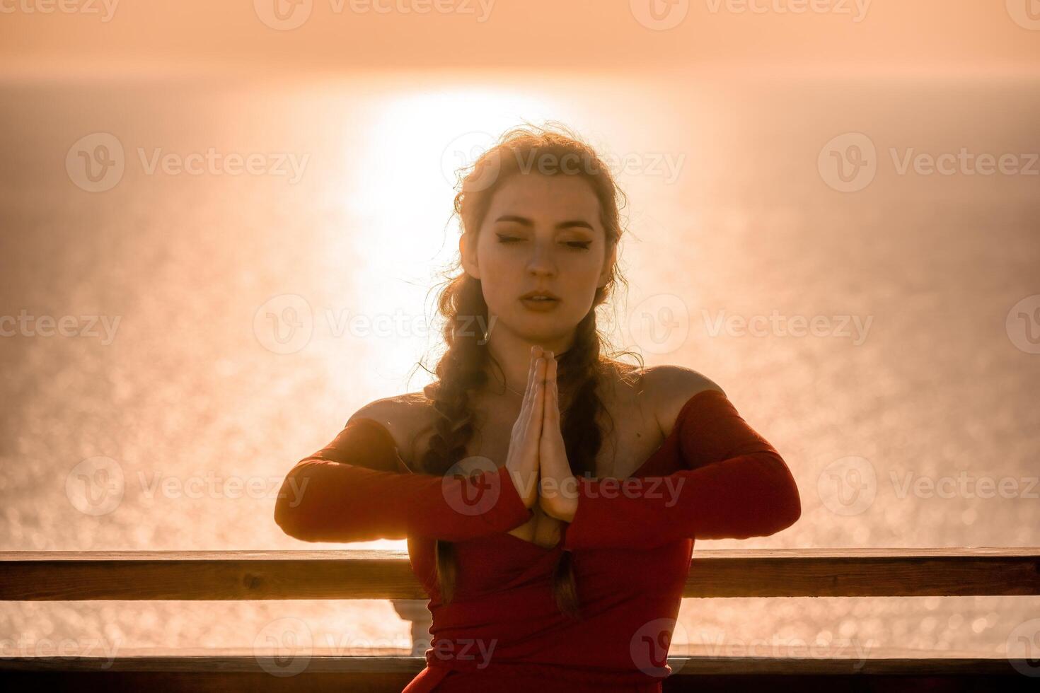 Closeup portrait of sensual young brunette woman in red dress, happily dancing outdoors isolated on blurry sea background with natural bokeh in soft warm sunset backlight. Selective focus. photo