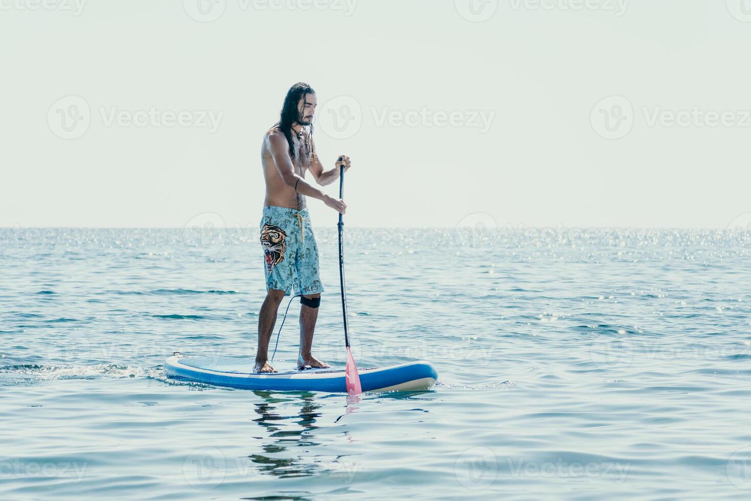 Man Sup Sea. Strong athletic man learns to paddle sup standing on board in open sea ocean on sunny day. Summer holiday vacation and travel concept. Aerial view. Slow motion photo