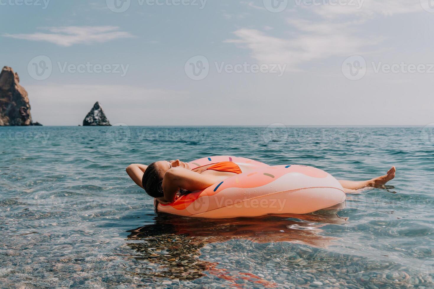 Summer Vacation Woman floats on an inflatable donut mattress, a water toy swim ring. Positive happy woman relaxing and enjoying family summer travel holidays vacation on the sea. Slow motion photo