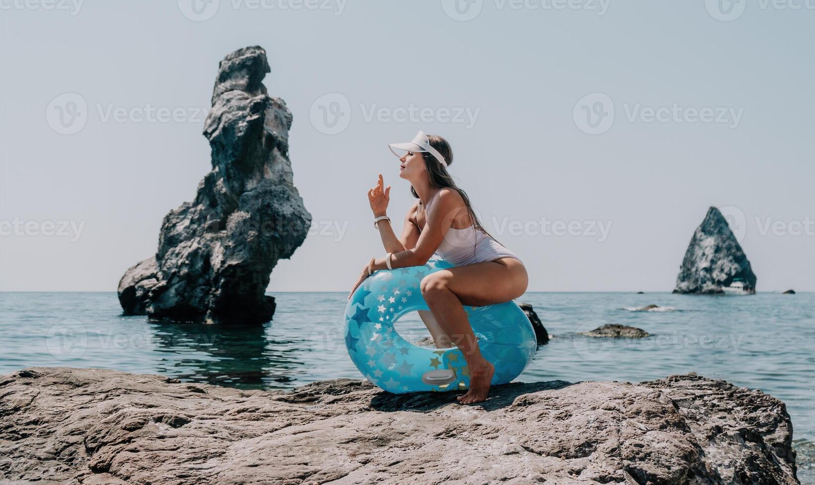 Woman summer sea. Happy woman swimming with inflatable donut on the beach in summer sunny day, surrounded by volcanic mountains. Summer vacation concept. photo