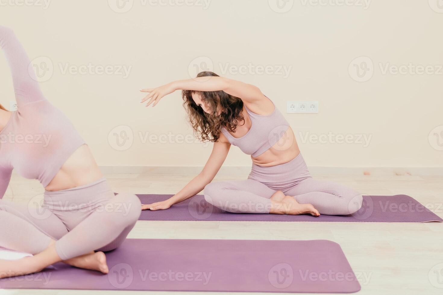 Well looking middle aged sporty woman, fitness instructor in pink sportswear doing stretching and pilates on yoga mat in the studio with mirror. Female fitness yoga. Healthy lifestyle and harmony. photo